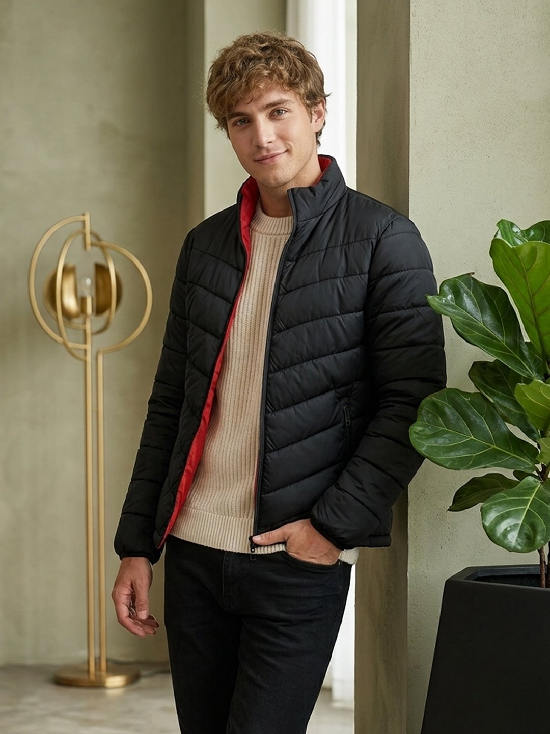 Men's black winter bomber jacket with padded design, red lining, and zip closure.